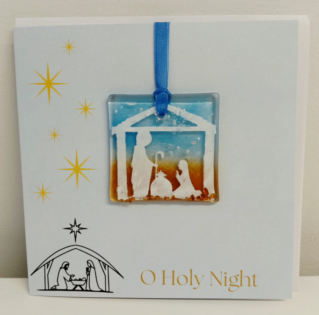 Handcrafted 6x6 inch “O Holy Night” Christmas greeting card featuring a detachable square fused glass nativity ornament with Joseph, Mary, baby Jesus in a manger silhouette against a sky blue and warm amber background.