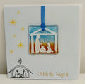 Handcrafted 6x6 inch “O Holy Night” Christmas greeting card featuring a detachable square fused glass nativity ornament with Joseph, Mary, baby Jesus in a manger silhouette against a sky blue and warm amber background.