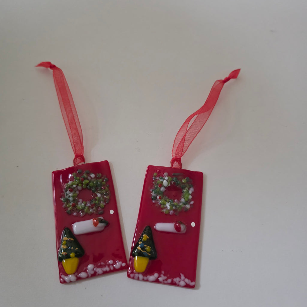 Handcrafted bright red fused glass festive front door tree ornament measuring 7x4cm, decorated with a textured wreath, letterbox, doorknob, potted mini Christmas tree, and snow dusting on a red hanging ribbon.